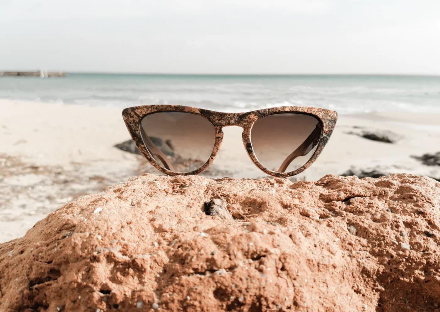 Zeyelo cat-eye sunglasses in seagrass on a sandy beach