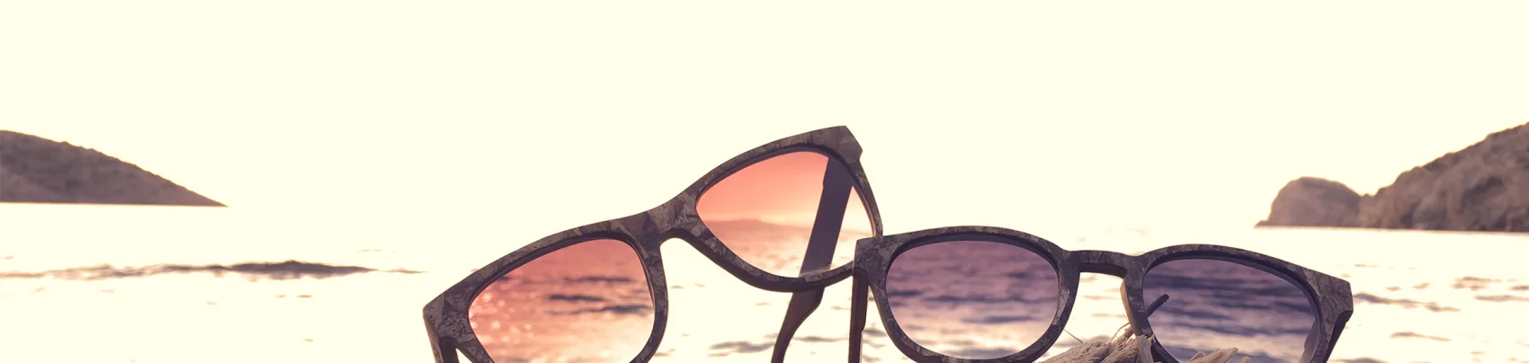 Zeyelo seagrass sunglasses resting on driftwood at sunset