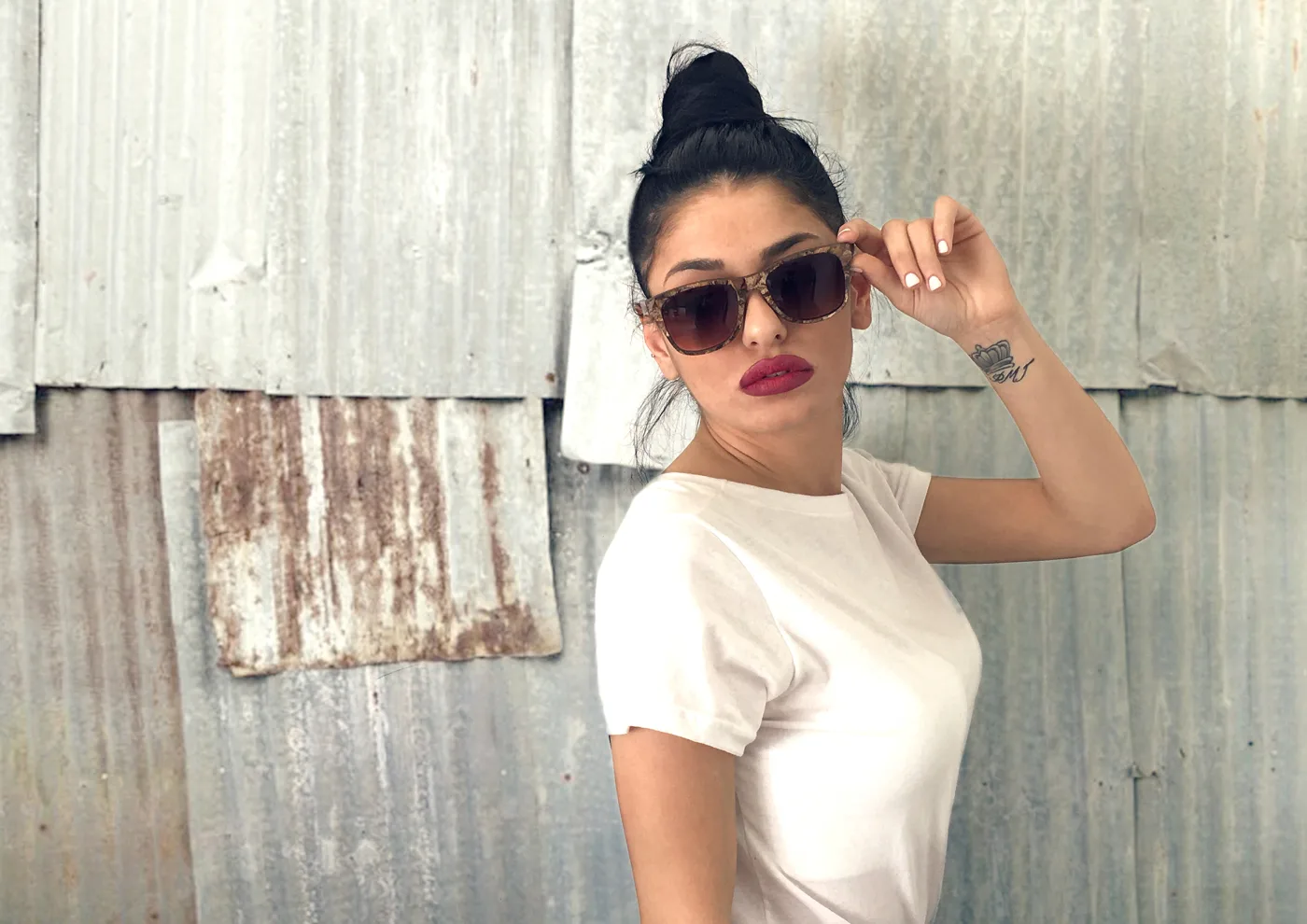 Zeyelo seagrass sunglasses worn against a weathered metal wall